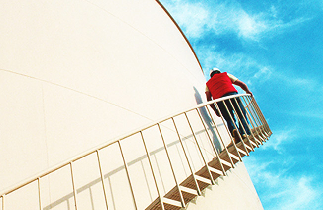 天然ガスタンクの外階段を登る人